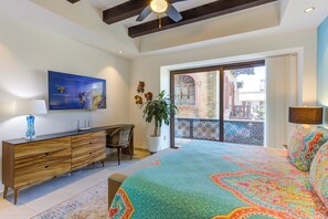 Ein Schlafzimmer mit Bett, Schreibtisch, Stuhl, Blumentopf und einem Balkon mit Blick.