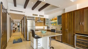 Una cocina moderna con una isla central, electrodomésticos de acero inoxidable, armarios de madera y un salpicadero de azulejos.