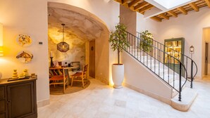 A spacious interior with a staircase, a dining area, and a large potted plant. - Casa Aura (Vejer de la Frontera)