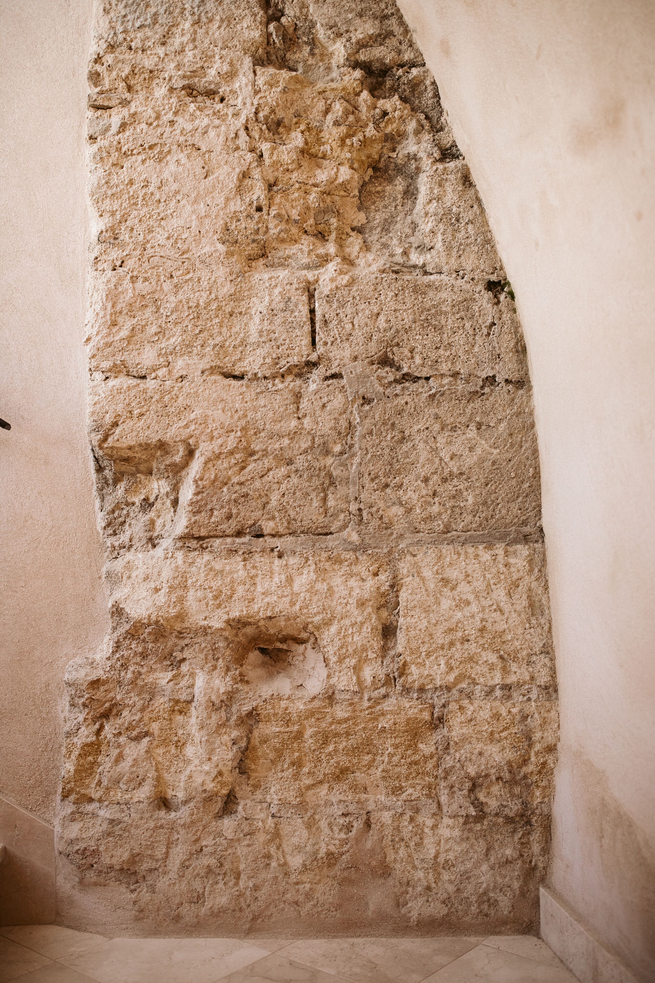 A stone wall with a rough texture and visible mortar joints.