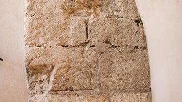 A stone wall with a rough texture and visible mortar joints.
