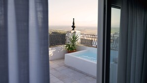 A balcony with a white bathtub, a potted plant, and a view of the countryside. - Casa Aura (Vejer de la Frontera)