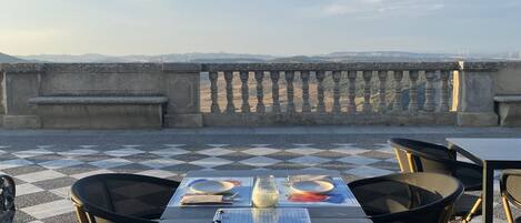Ein Esstisch mit Blick auf entfernte Windkraftanlagen, einem Schachbrettmuster im Boden und einem klaren Himmel.