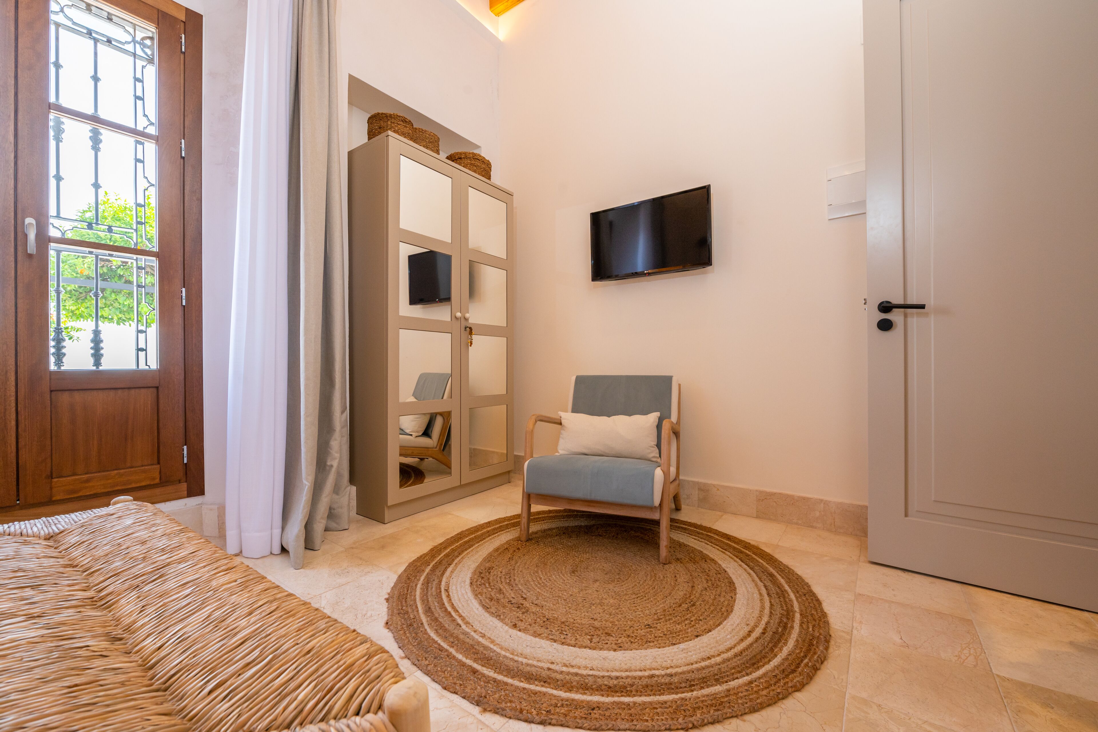 A room with a bed, a chair, a television, and a wardrobe.