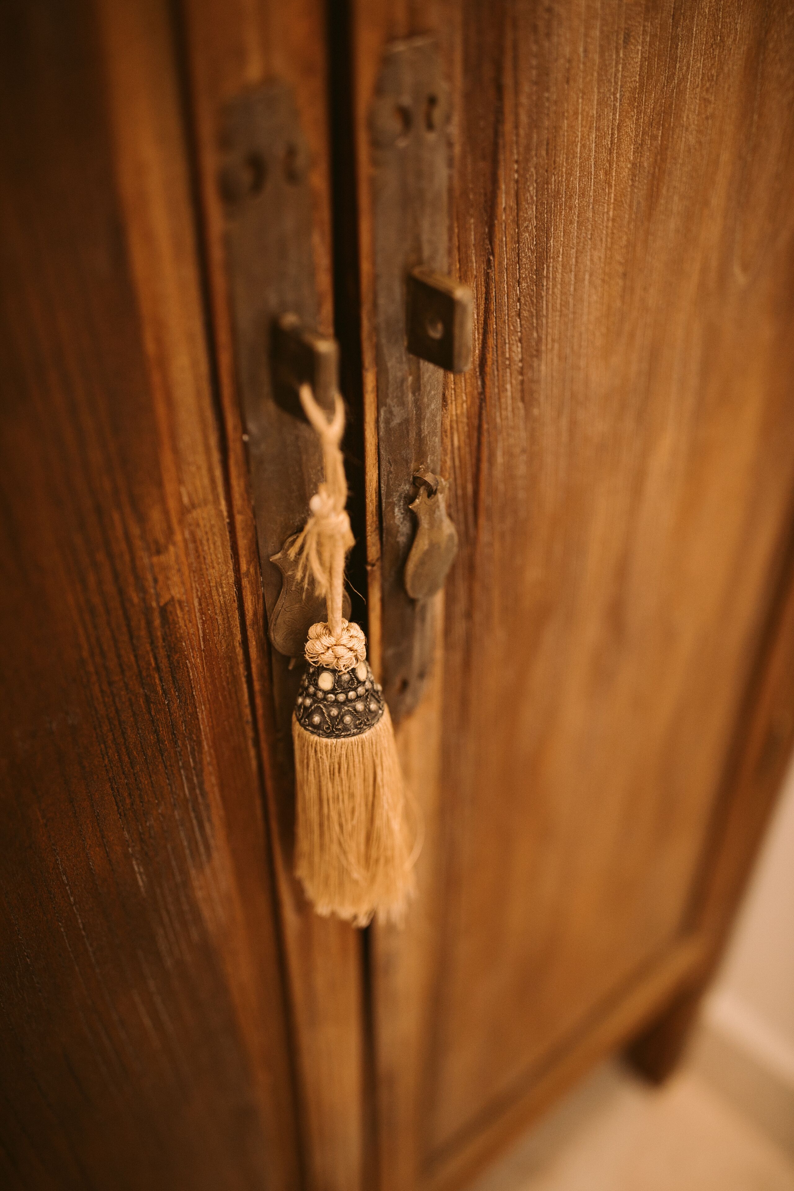 Una puerta de madera con un picaporte de latón y un fleco decorativo.