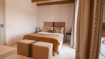 Un dormitorio con cama, mesitas de noche, un banco y cortinas.