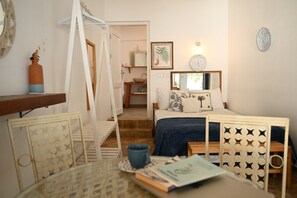 A bedroom with a bed, bedside table, chair, and a small table with books.