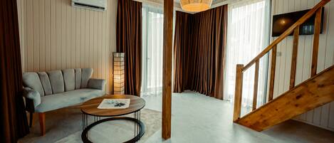 Un salon moderne avec un canapé, une table basse et un escalier en bois.