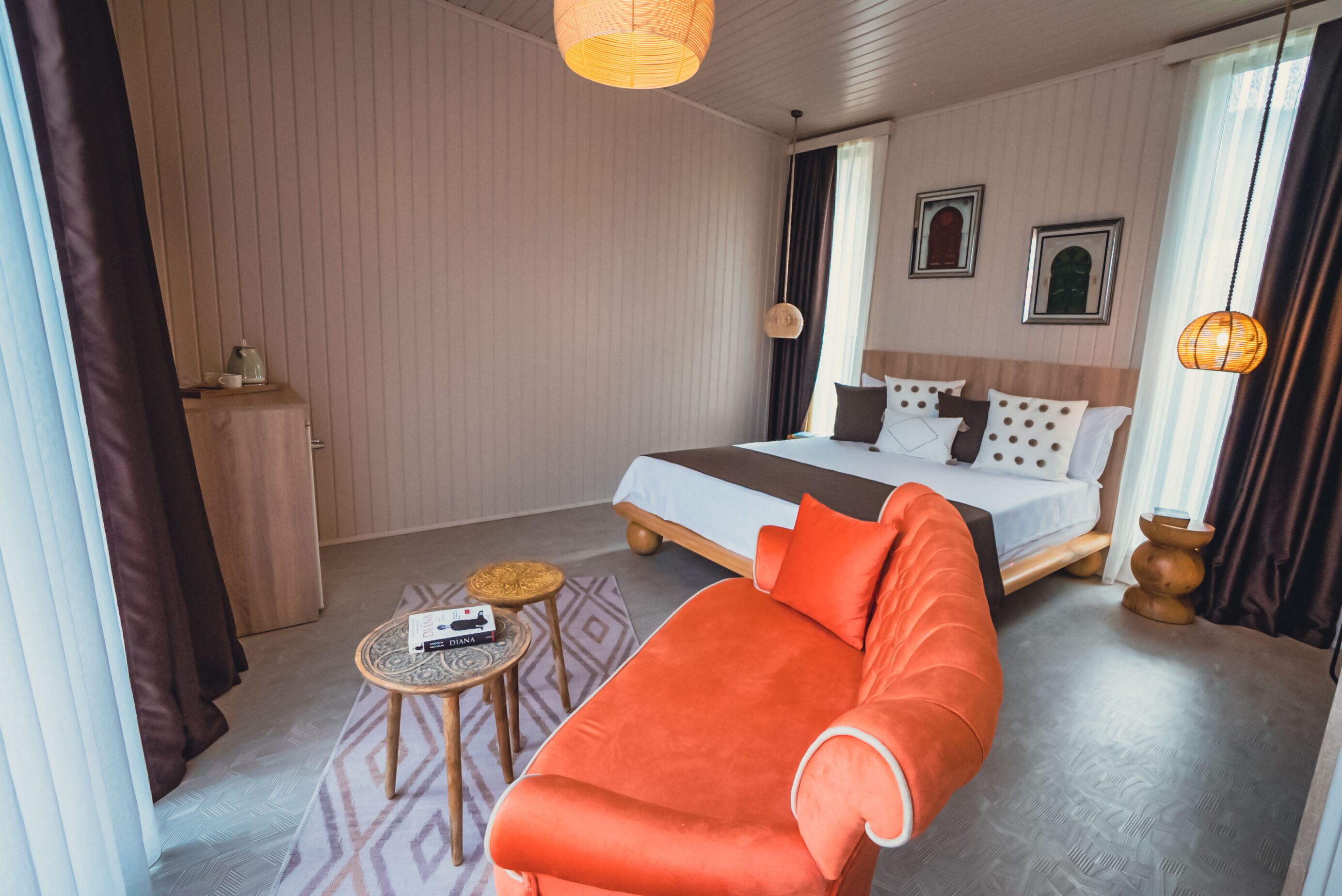 A hotel room with a bed, orange sofa, small round table, and a wardrobe.