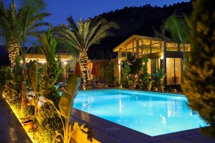 Una piscina rodeada de plantas tropicales y un edificio con amplias ventanas.