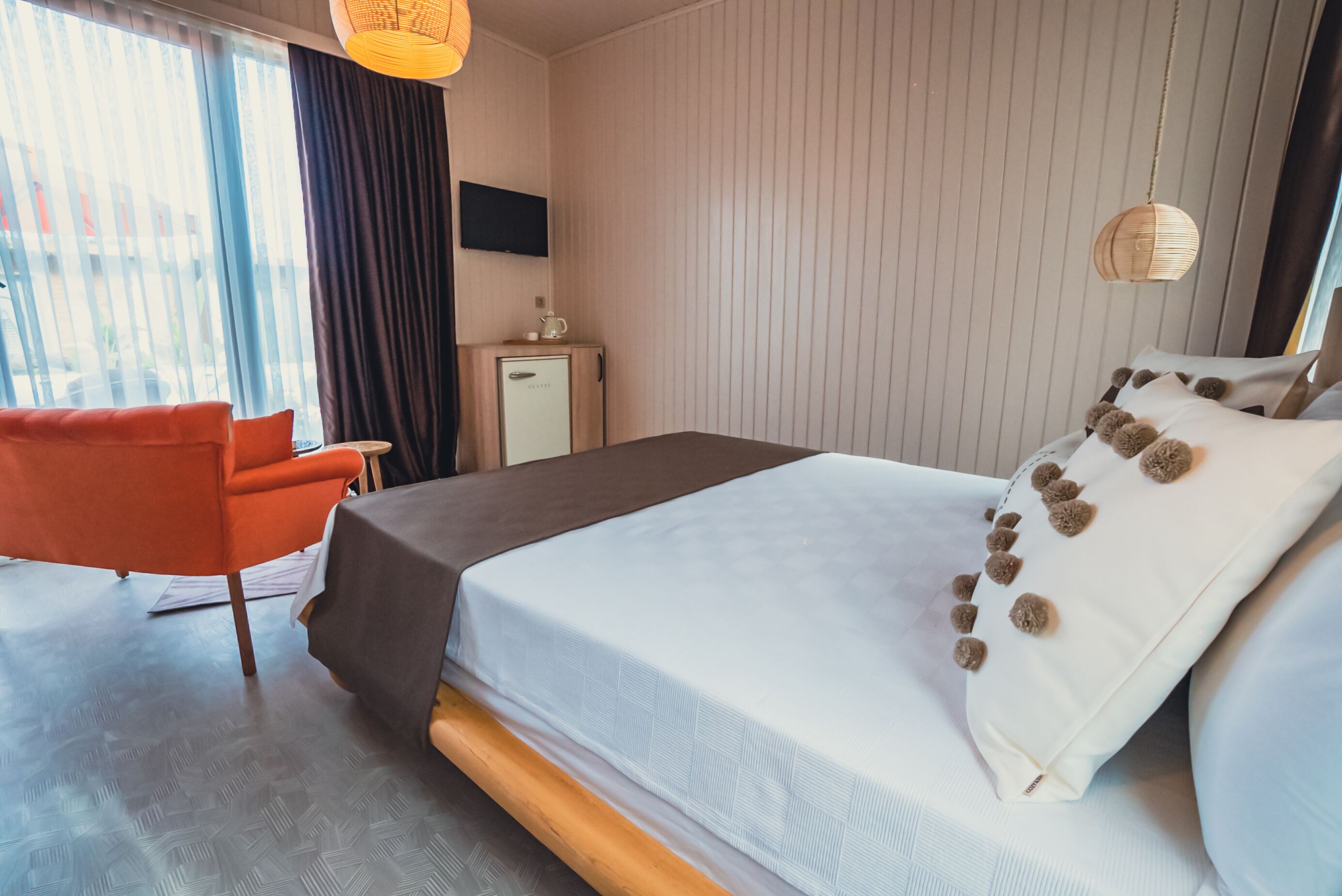 A hotel room with a bed, a desk, a chair, a television, and a window with curtains.