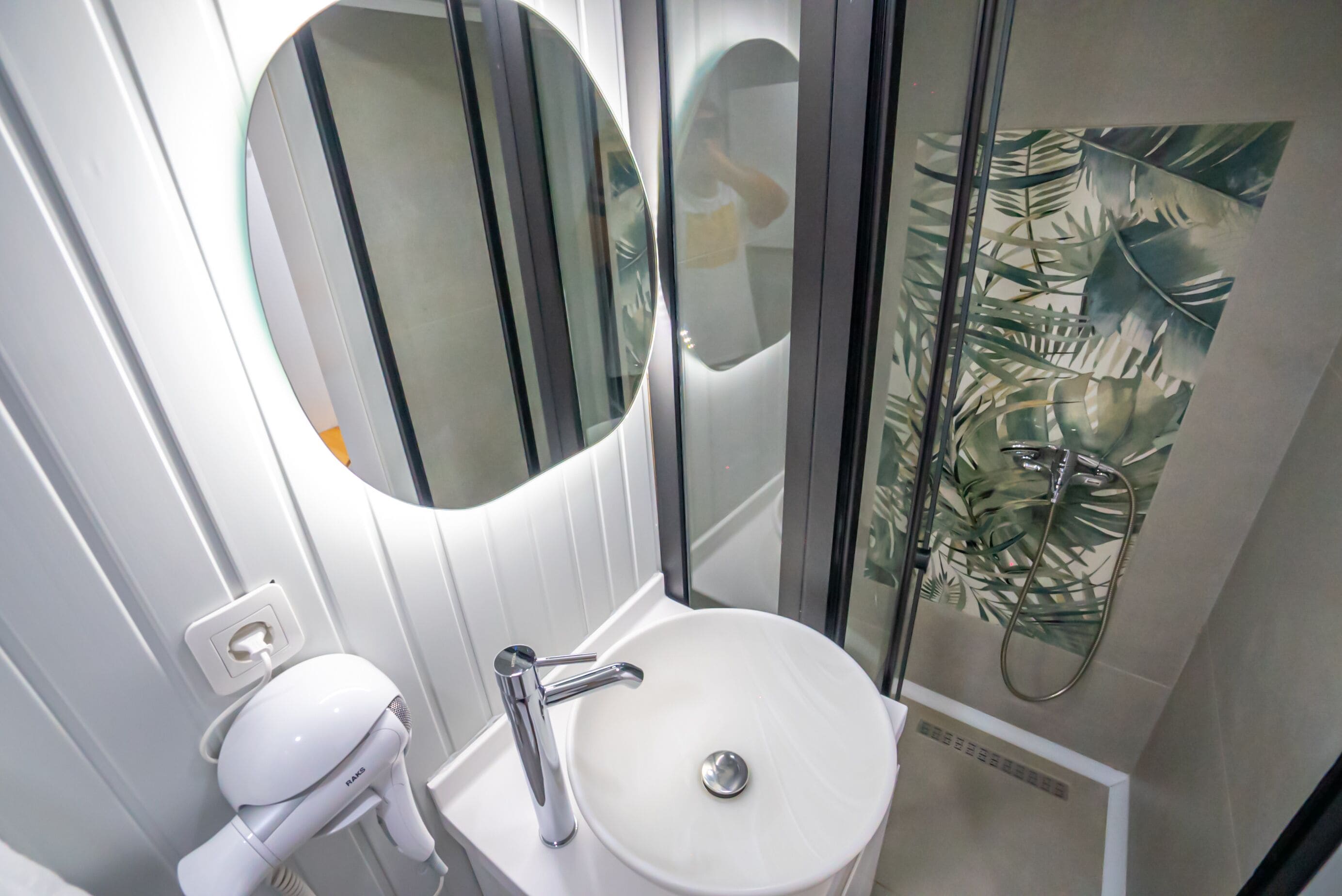 Un baño con un lavabo blanco, un espejo y una ducha.