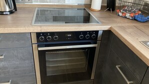 A modern kitchen with a built-in oven and stovetop, a coffee maker, and a knife block.