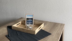 A wooden table with a tray holding a framed sign and a glass. Four framed signs are on the wall.