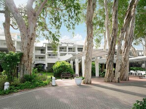 Un hôtel doté d’un espace extérieur abrité, d’arbres et d’un panneau indiquant « The Beach Club ».