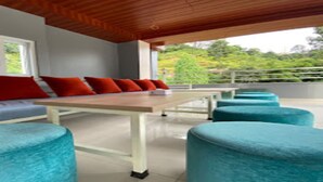 Een modern terras met een houten tafel en blauwe, beklede krukken.