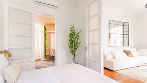 Une chambre à coucher moderne avec un grand lit, un canapé blanc et un miroir au mur.
