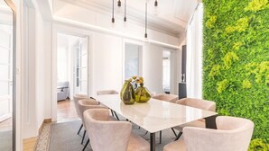 Une salle de conférence moderne avec une table blanche, des chaises beiges et un mur végétal vertical vert.