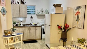 A modern kitchen with wooden cabinets, a white refrigerator, and a dining area with a glass table and chairs. - Unidad 1 - Casa Cuatro Palmas 🌴 (rincon)