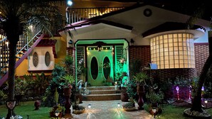 A well-lit entrance with a green-lit door, a staircase, and a variety of potted plants and outdoor lighting. - Unidad 1 - Casa Cuatro Palmas 🌴 (rincon)