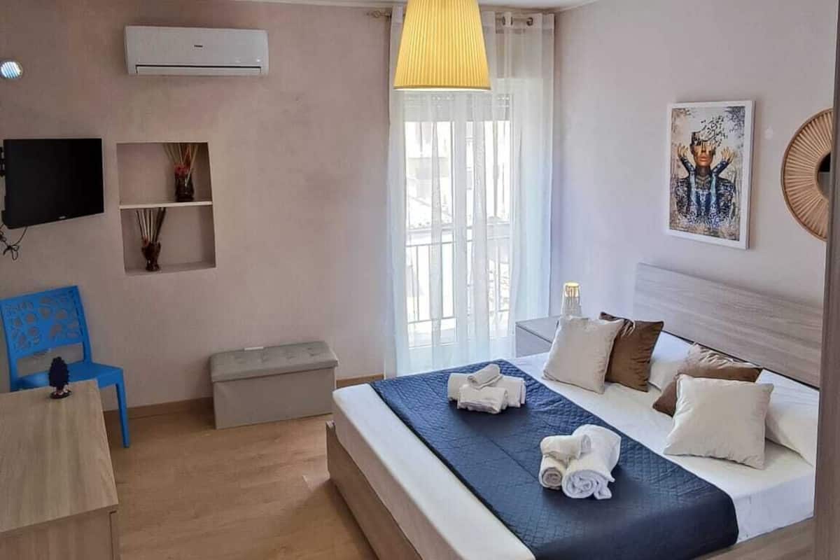 Ein modernes Schlafzimmer mit einem großen Bett, einem Fernseher, einem kleinen Tisch und einem blauen Stuhl.