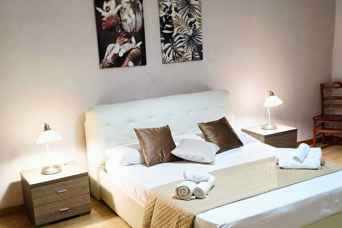 Ein modernes Schlafzimmer mit einem großen Bett, zwei Nachttischen, einem Beistelltisch und einer Pendelleuchte.