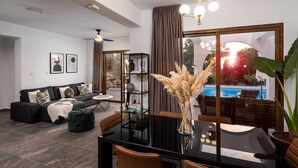 Una sala de estar moderna con una mesa de comedor negra, un sofá y vistas a una piscina.
