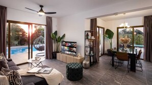 Una sala de estar moderna con vista a la piscina, ventilador de techo y comedor con mesa y sillas.