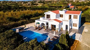 Una villa blanca con piscina, varios balcones y vistas del paisaje circundante.