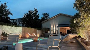 A wooden deck with lounge chairs, a small pool, and a stone wall. - Maison de Charme (Valence)