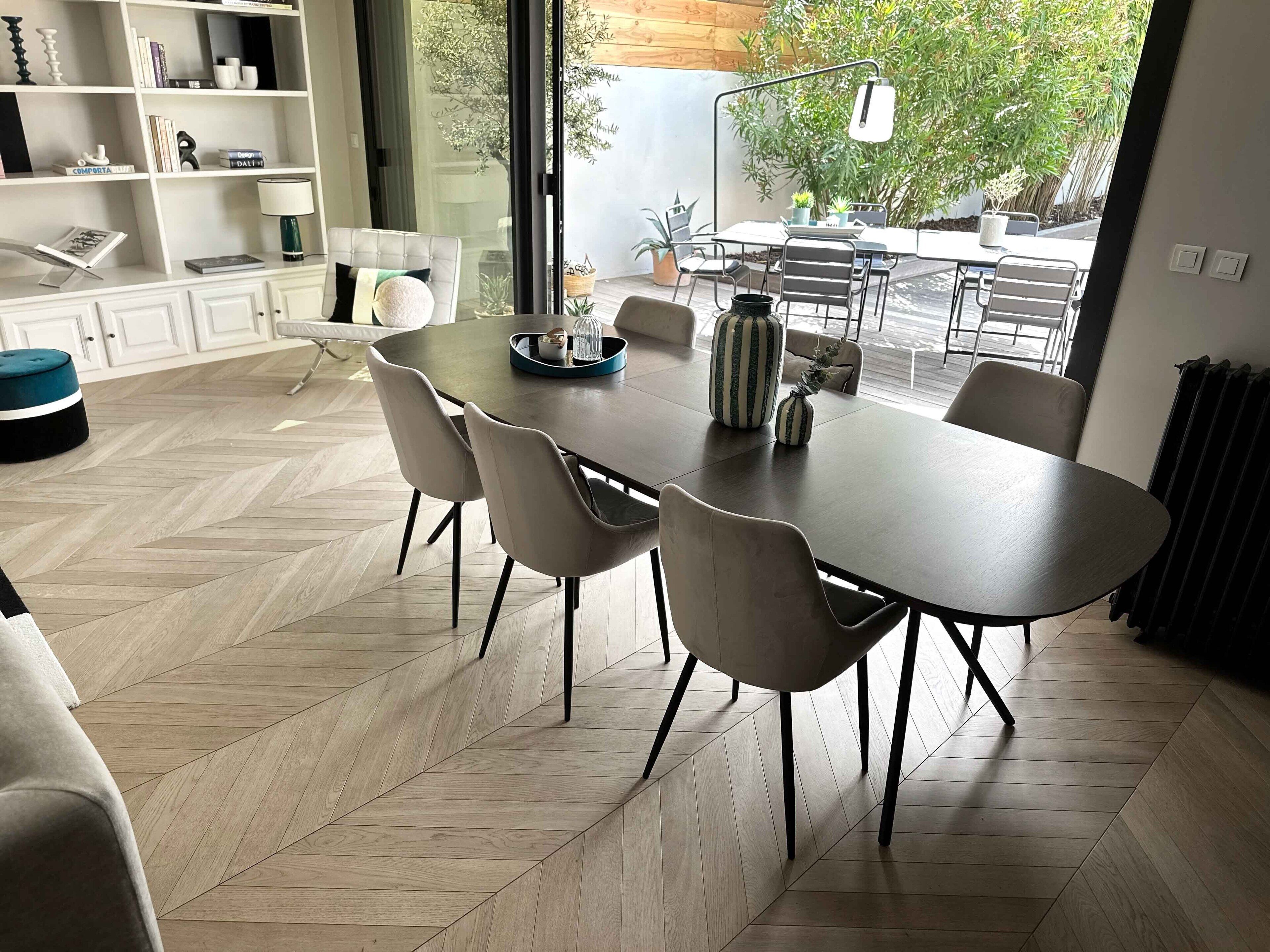Een moderne eethoek met een grote tafel, stoelen en uitzicht op de omgeving.