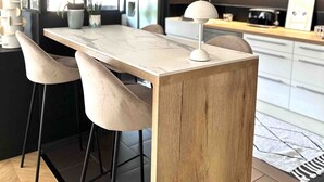 A modern kitchen with a wooden island, bar stools, and pendant lighting. - Maison de Charme (Valence)
