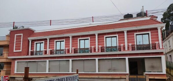 Un immeuble de deux étages avec une façade rouge, de nombreuses fenêtres et des balcons dotés de rampes.