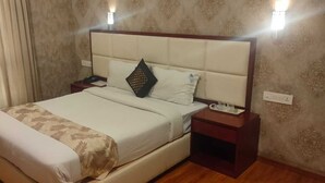 Ein Hotelzimmer mit einem großen Bett, einem Nachttisch, einer Wandleuchte und einer Lampe.
