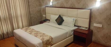Una habitación de hotel con una cama grande, una mesita de noche y una lámpara de pared.