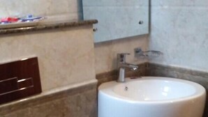 Ein Badezimmer mit einem weißen Waschbecken, einer Toilette und einem Mülleimer.