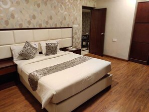 Une chambre à coucher avec un grand lit, deux tables de chevet, un plancher en bois et un papier peint à motifs.