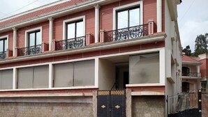 Ein zweistöckiges Gebäude mit einem Balkon im oberen Geschoss, großen Fenstern und einem schwarzen Tor am Eingang.
