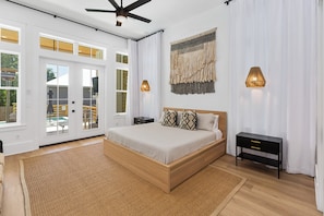 A spacious bedroom with a large bed, a wooden headboard, a nightstand, and a black side table. There are two wall-mounted lamps and a ceiling fan. - NEW-Family Friendly, Private Pool, short walk to beach- discount on rental gear! (Santa Rosa Beach)