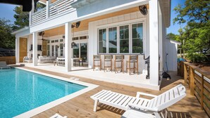 Een moderne woning met een zwembad, buitenzitplaatsen en een overdekt terras.