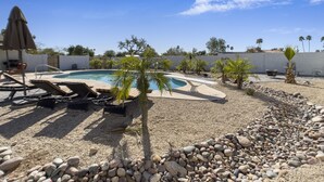 A pool area with lounge chairs, palm trees, and a clear blue sky. - Gorgeous and private ranch on expansive 1.2 acres (Scottsdale)