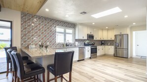 A modern kitchen with a large island, white cabinets, stainless steel appliances, and a patterned backsplash. - Gorgeous and private ranch on expansive 1.2 acres (Scottsdale)