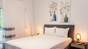 A neatly made bed with white linens, a grey upholstered headboard, and two bedside tables with lamps. - Elegant Urban Escape Apt in Kolonaki (Athens)