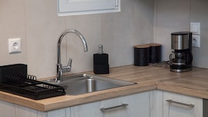 A modern kitchen with a stainless steel sink, a coffee maker, and black storage containers. - Elegant Urban Escape Apt in Kolonaki (Athens)