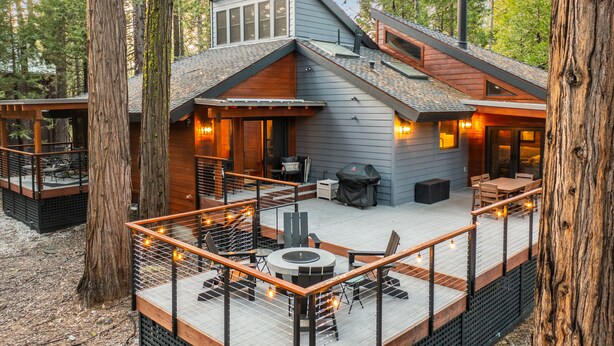 Eine moderne Holzhütte mit Terrasse, Sitzgelegenheit im Freien und einem Feuerkorb.