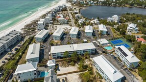 Vista aerea di una località balneare con diversi edifici, una spiaggia e una vasta distesa d'acqua.
