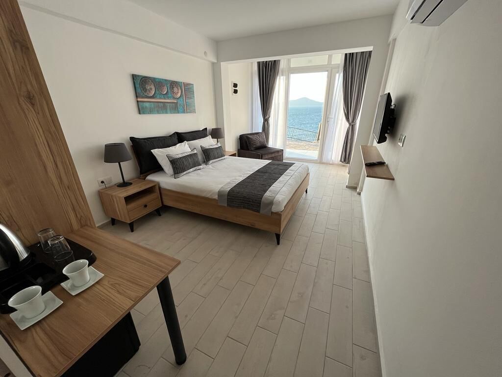 Une chambre d’hôtel avec un lit, une table de chevet et vue sur la mer.