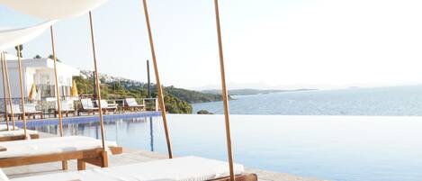 A poolside area with lounge chairs and a view of the sea.