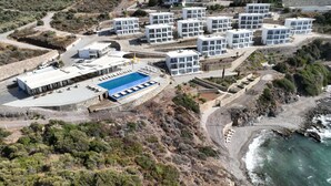 An aerial view of a coastal hotel with multiple white buildings, a swimming pool, and a rocky shoreline. - Ni Marin Hotel (Milas)
