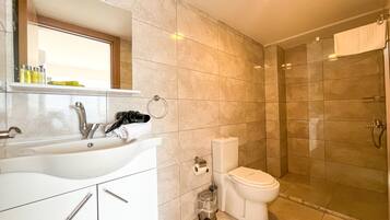 Un baño moderno con lavamanos, inodoro y ducha.